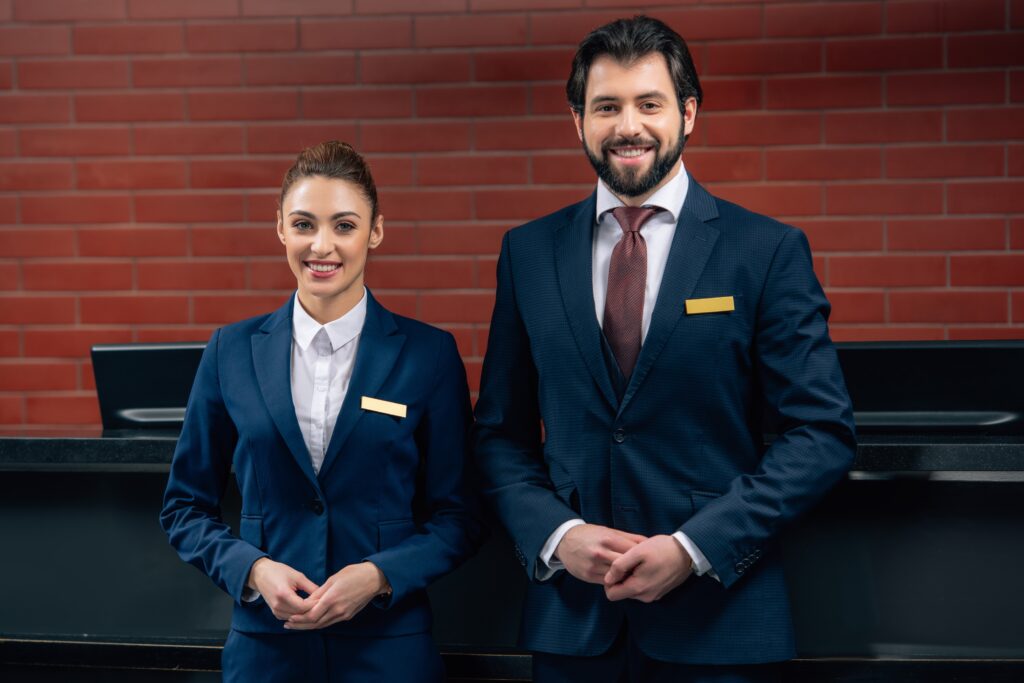 hotel receptionists in uniform standing together in front of counter